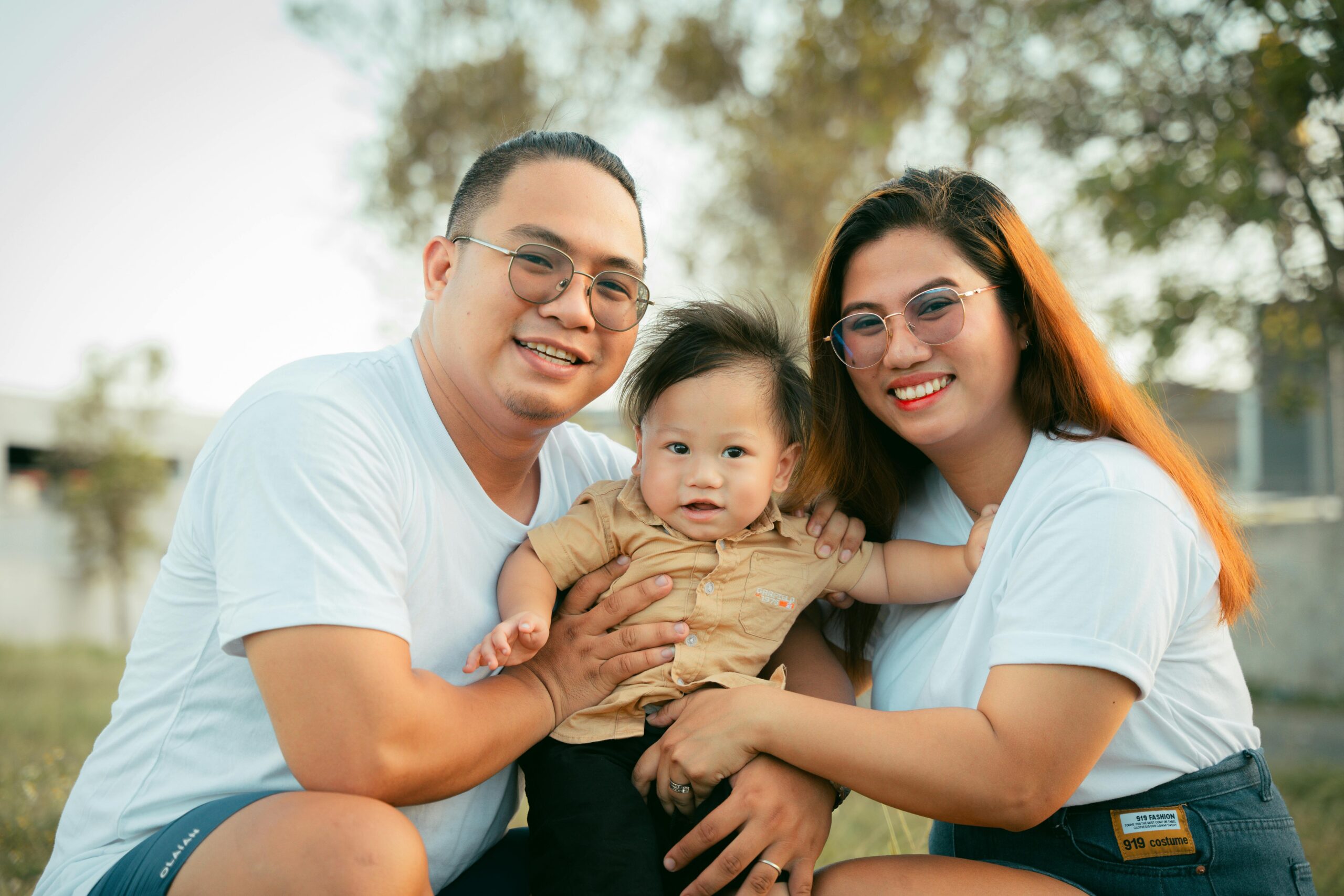 Smiling family with a young child enjoying a sunny day outside, creating joyful memories.