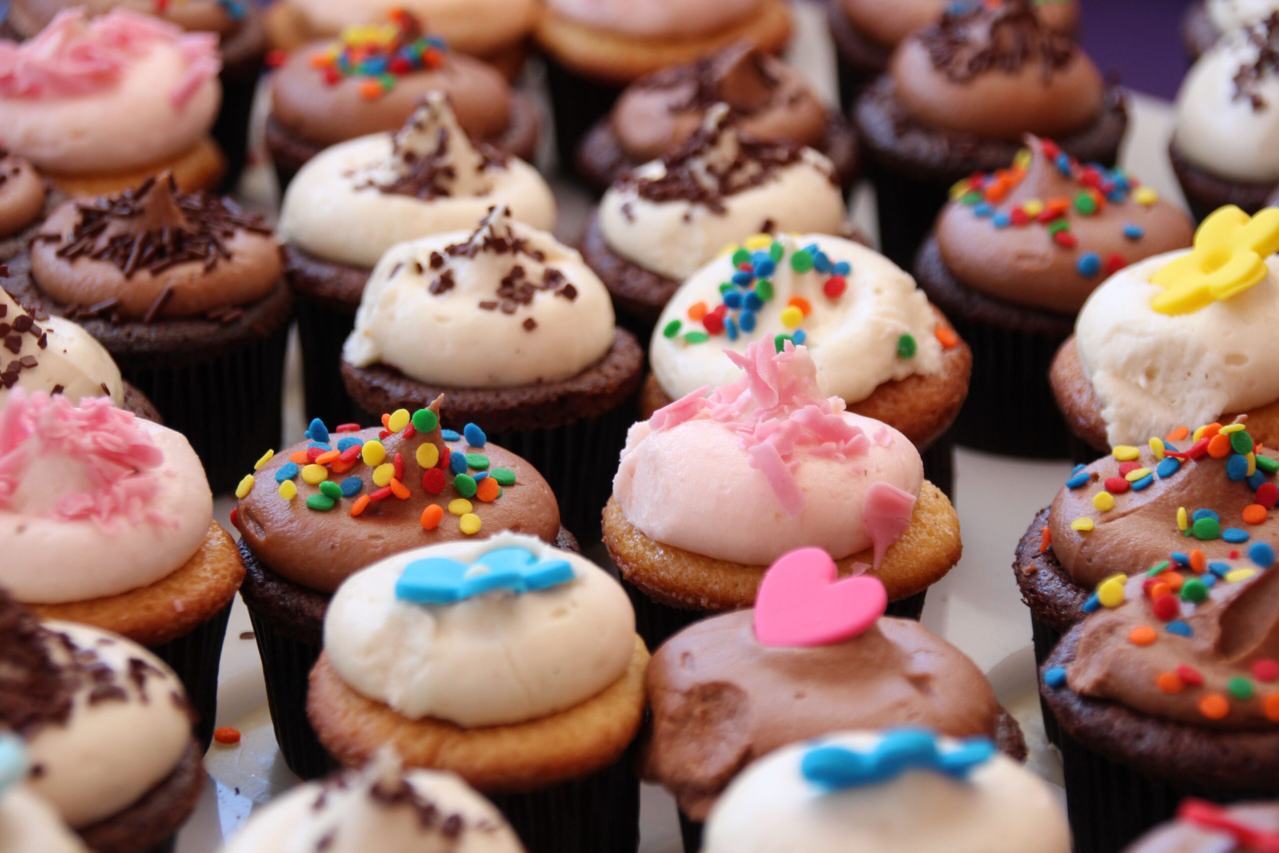 Close-up view of colorful decorated cupcakes with sprinkles and frosting.